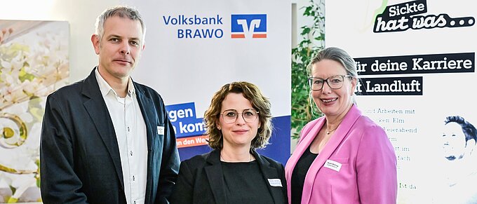 Drei Personen posieren vor einem Volksbank BRAVO und Karriere-Event-Banner.