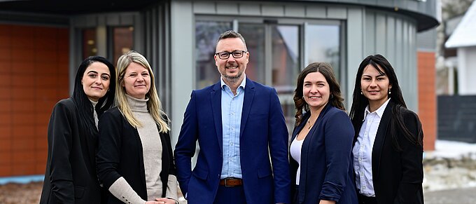 Fünf Personen in Businesskleidung vor einem Volksbank-Gebäude lächeln in die Kamera.