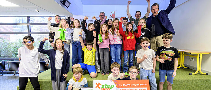Eine Gruppe von Kindern und Erwachsenen jubelt mit Urkunden und step-BRAWO Pokalen in der Hand.